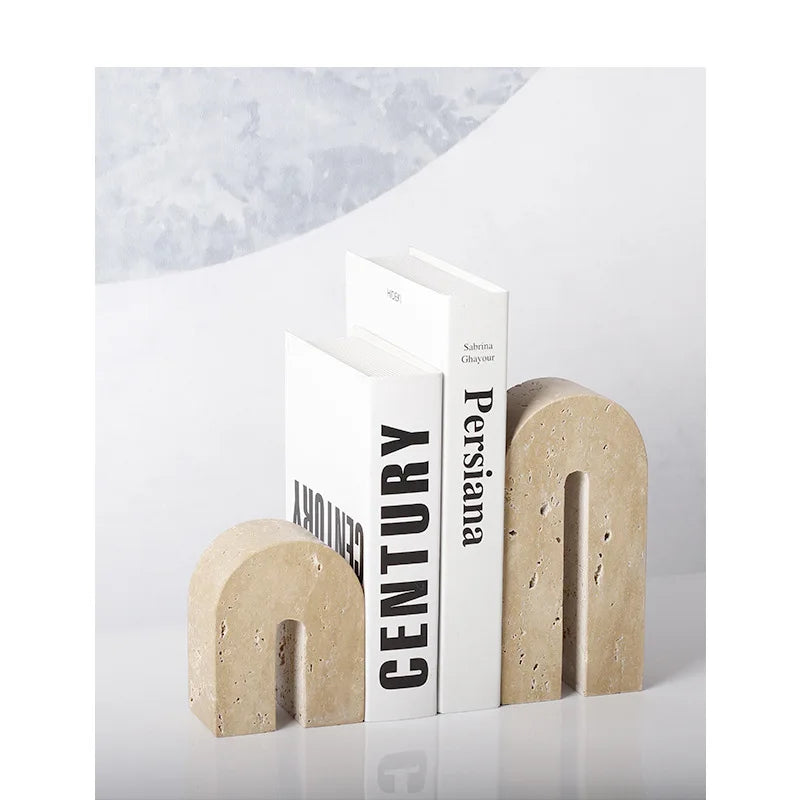 Pair of arched travertine bookends arranged with monochrome books against a light wall