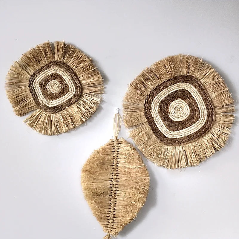 Cluster of round and leaf-shaped raffia wall hangings displayed against a white wall