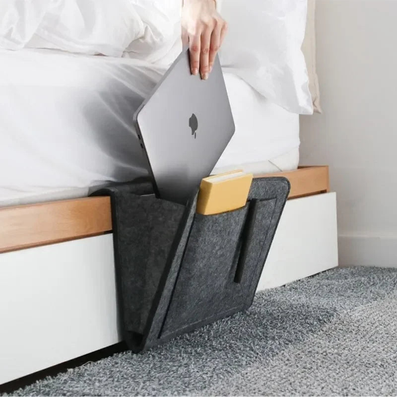 felt bedside organizer caddy storing a laptop and book at the side of a bed