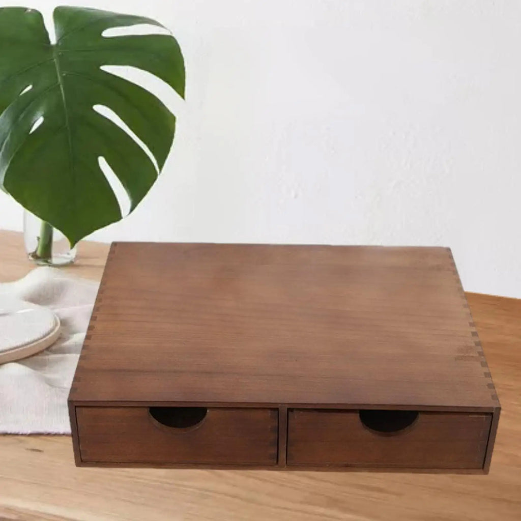 Brown wooden two-drawer organizer closed, on a light wood surface with a green leaf nearby