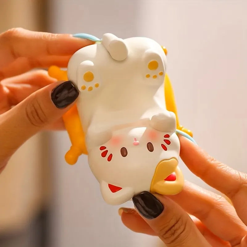 hand holding the cat-shaped white and yellow stand, showing its compact size