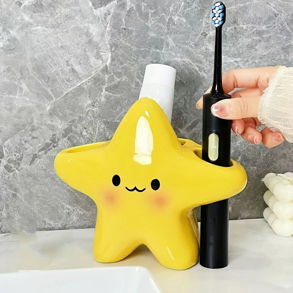 Person placing a black electric toothbrush into a yellow star-shaped toothbrush holder on a counter