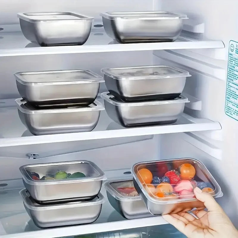 stainless steel containers in a refrigerator, some filled with fruit and vegetables, one being held by a hand