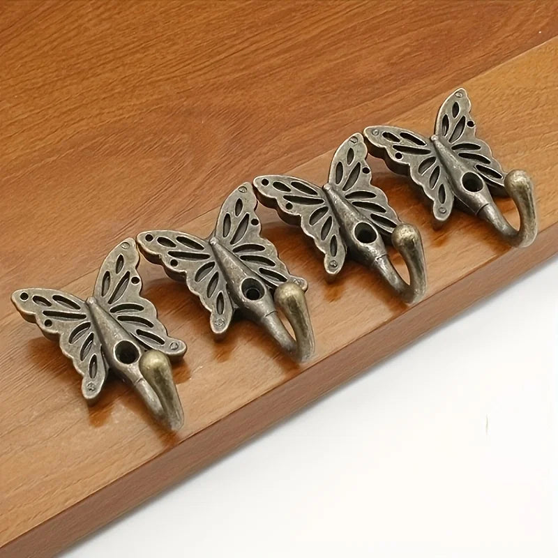 Set of four vintage butterfly cast iron wall hooks arranged on wooden surface