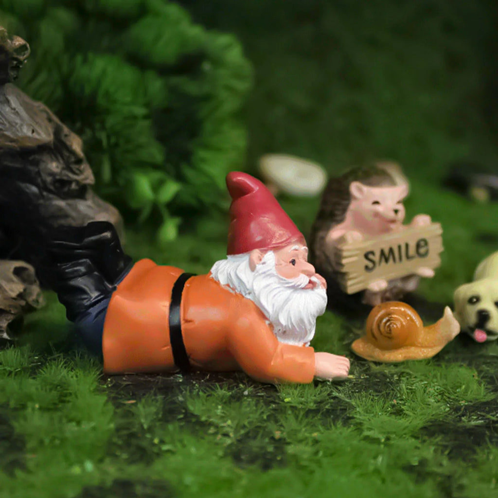 Mini resin gnome figure laying near other animal figurines in a garden setting