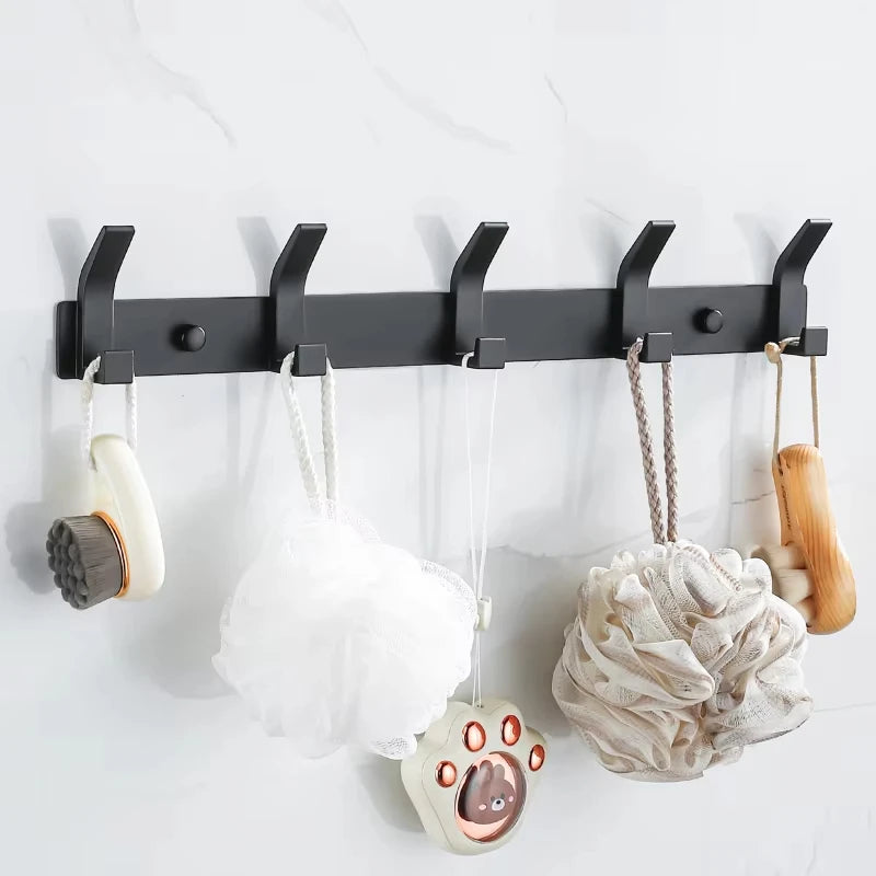 Wall-mounted black metal hook rack holding bath accessories in a bathroom