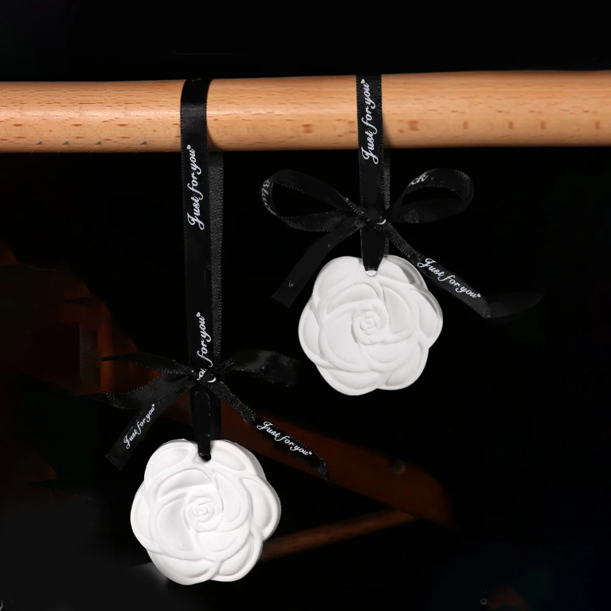 Camellia ceramic fragrance diffuser hanging on a wire basket with daisies nearby