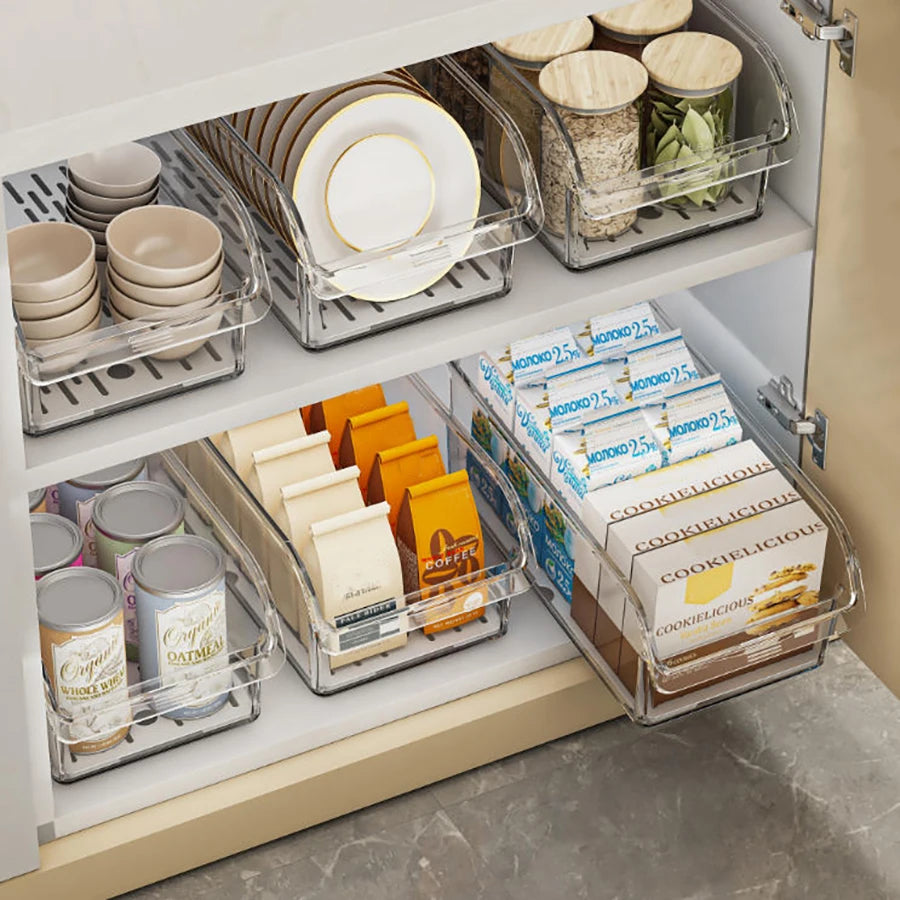Clear bins organizing pantry shelves with plates, small bowls, jars, boxes, and packets.