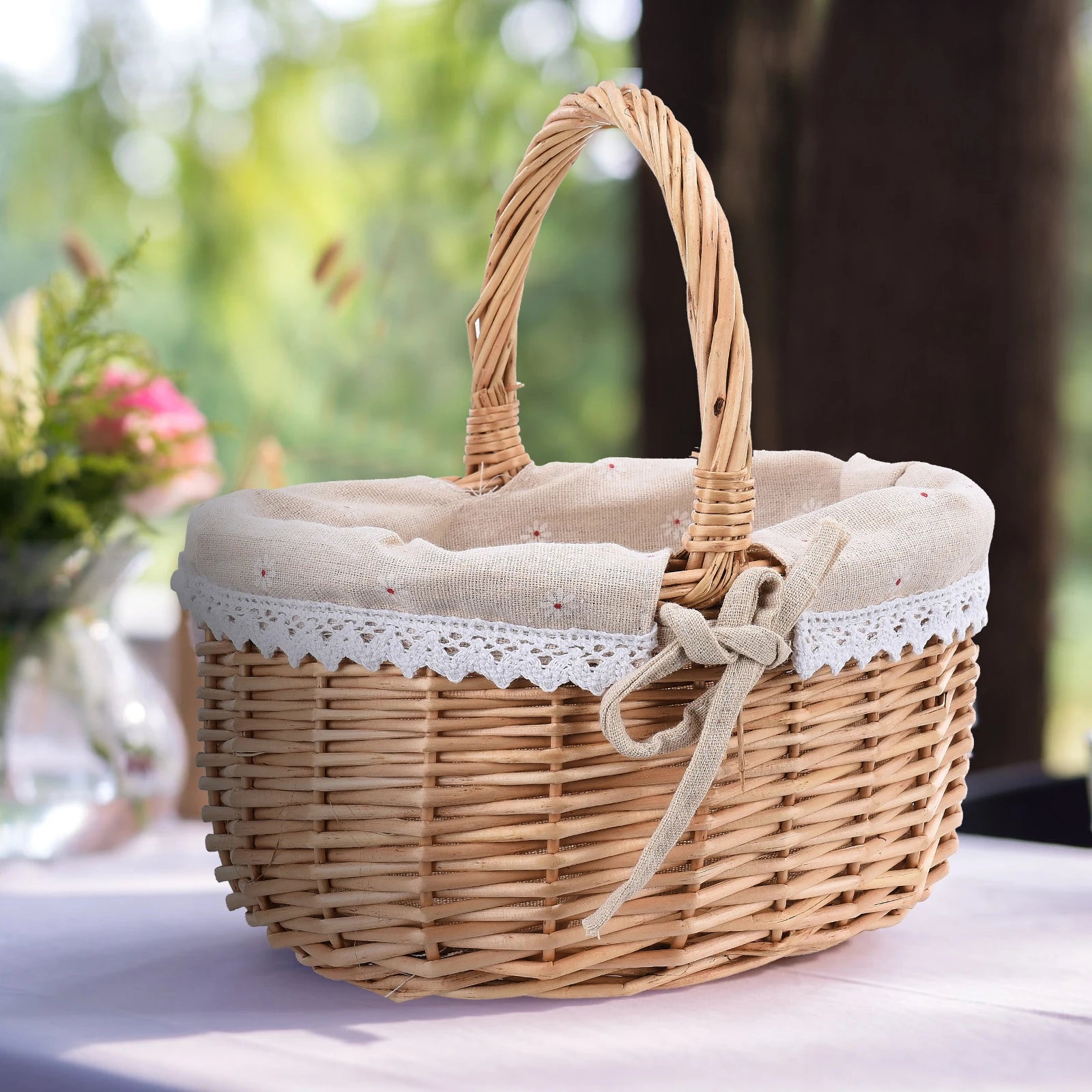 Handwoven rattan oval storage basket with floral fabric liner and handle on a table