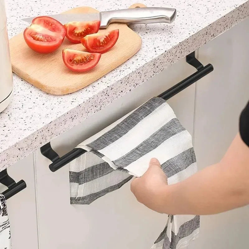 Person reaching for a striped dish towel on a black over-cabinet towel bar beneath a kitchen counter