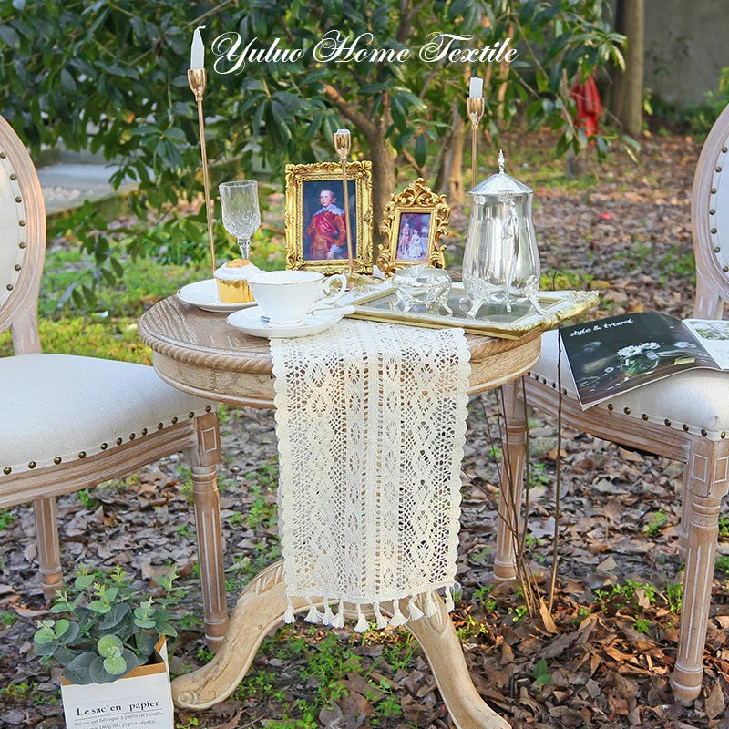 Crochet lace table runner on small round outdoor table set for tea with vintage decor