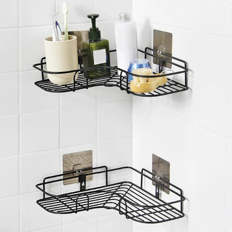 Adhesive stainless steel corner shelf holding rolled towel, toothbrush cup, and foaming facial cleanser in a bathroom setting.