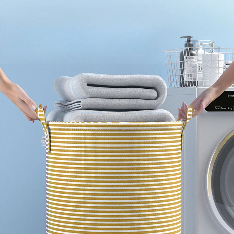 Two hands lifting a yellow striped laundry basket filled with folded towels