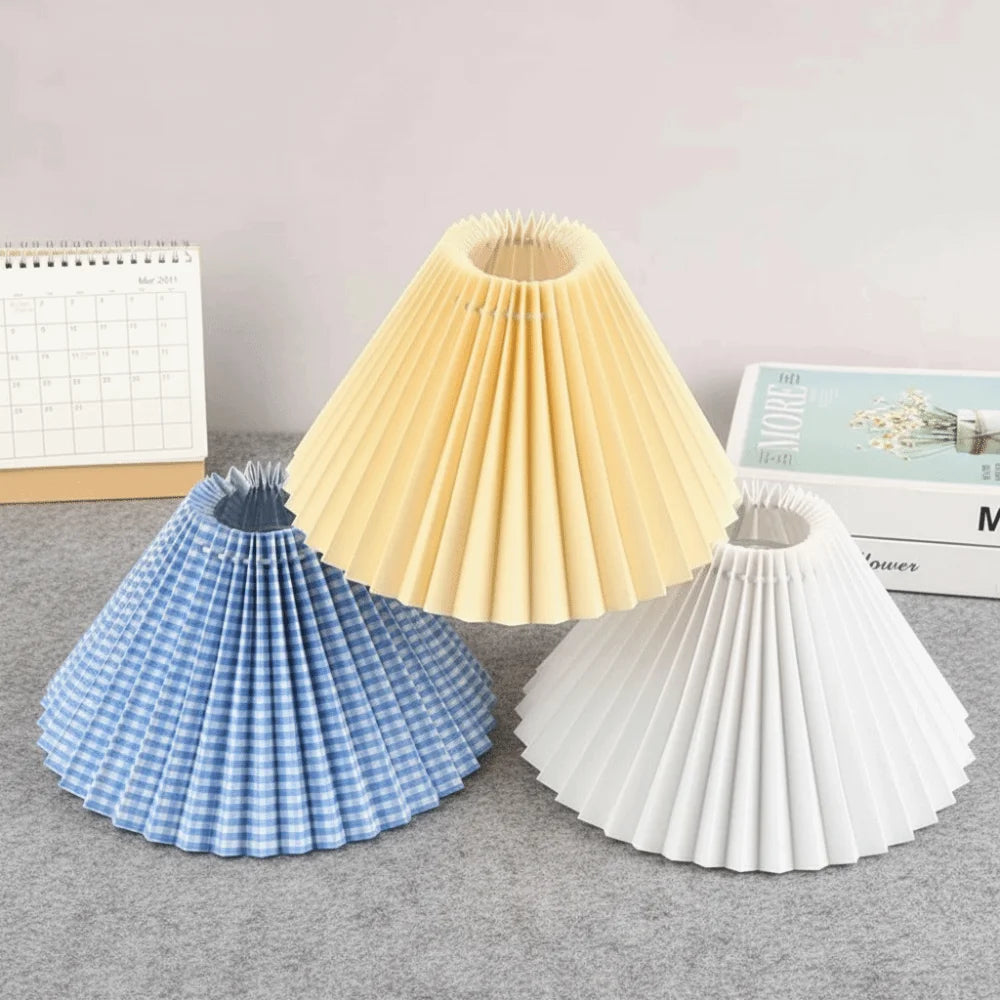 Yellow, blue checkered, and white cone-shaped pleated lampshades on a table