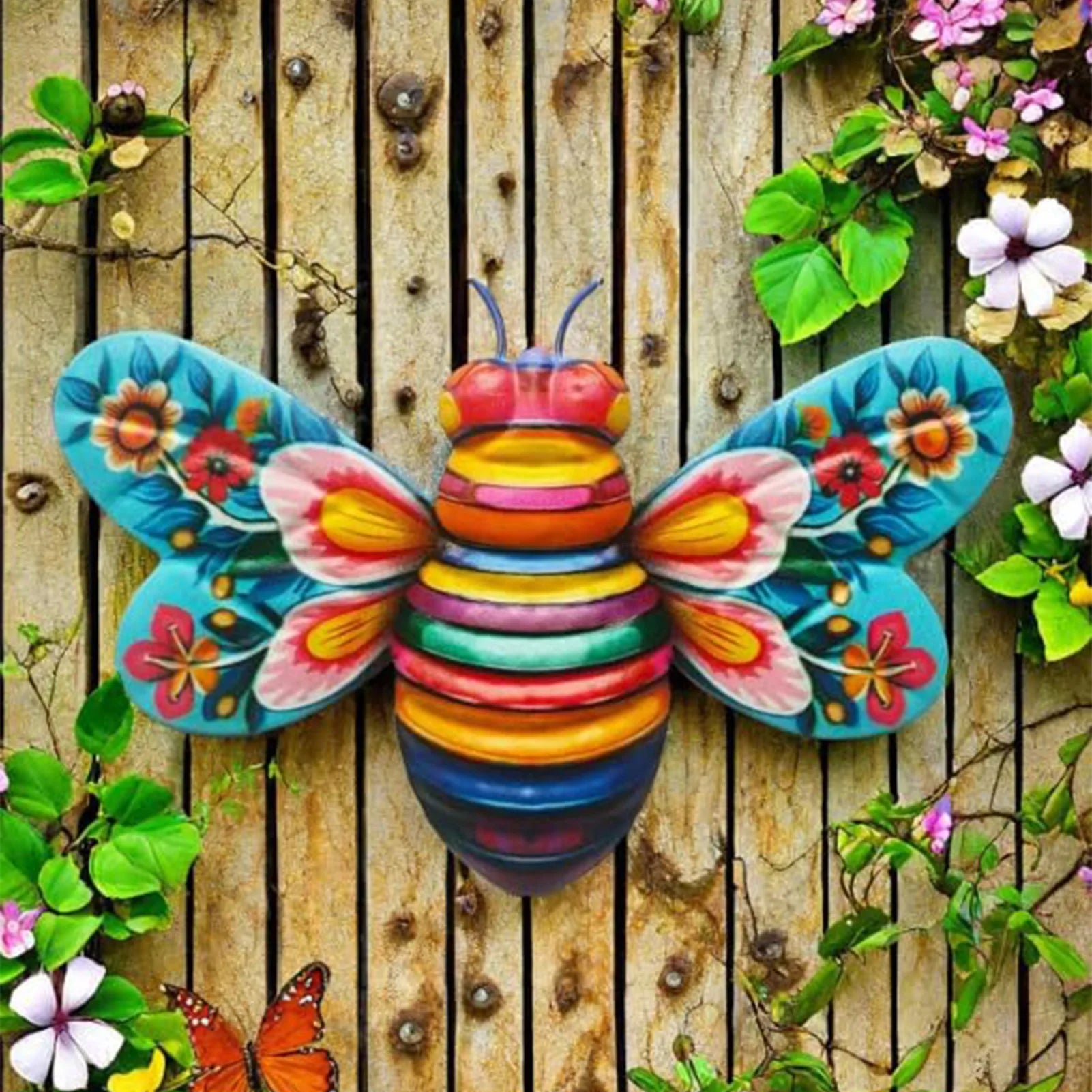 Colorful 3D bee metal wall art mounted on a garden fence surrounded by flowers