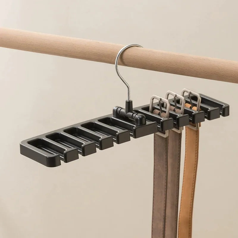 Black rotating belt and scarf hanger holding several belts on a wooden closet rod