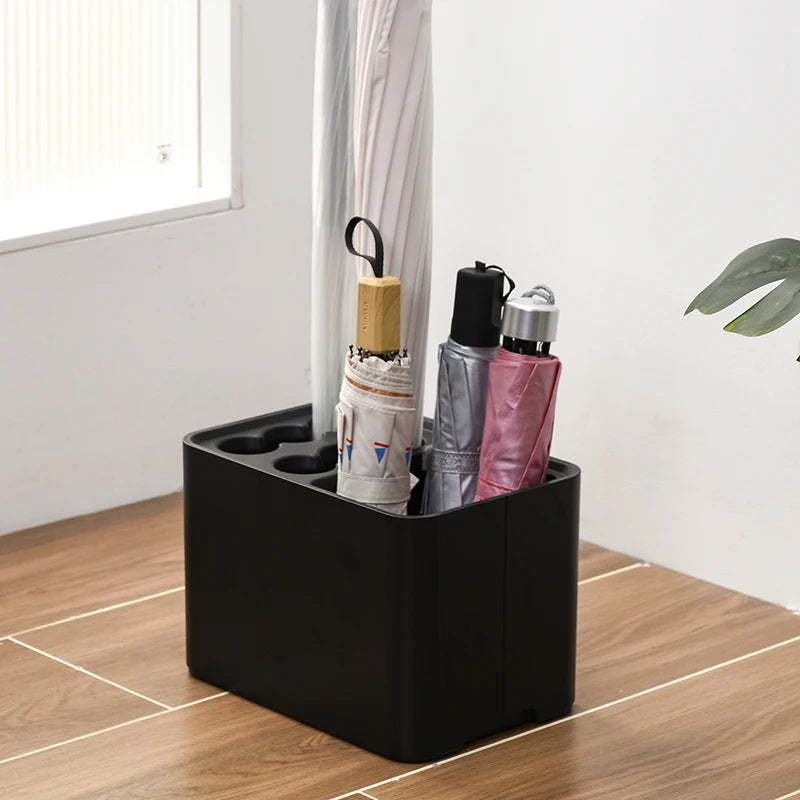 Black plastic umbrella stand storing umbrellas in a tidy, modern foyer