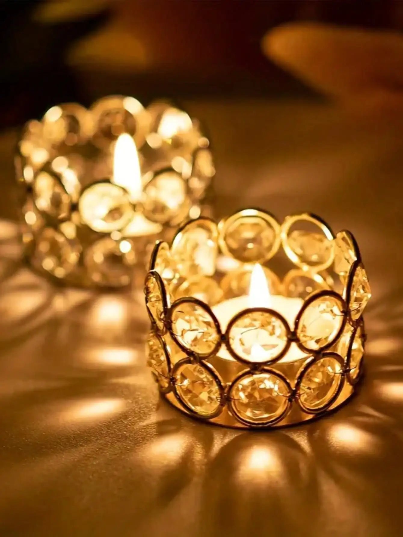 Close-up of a lit gold crystal tealight holder glowing warmly on a table
