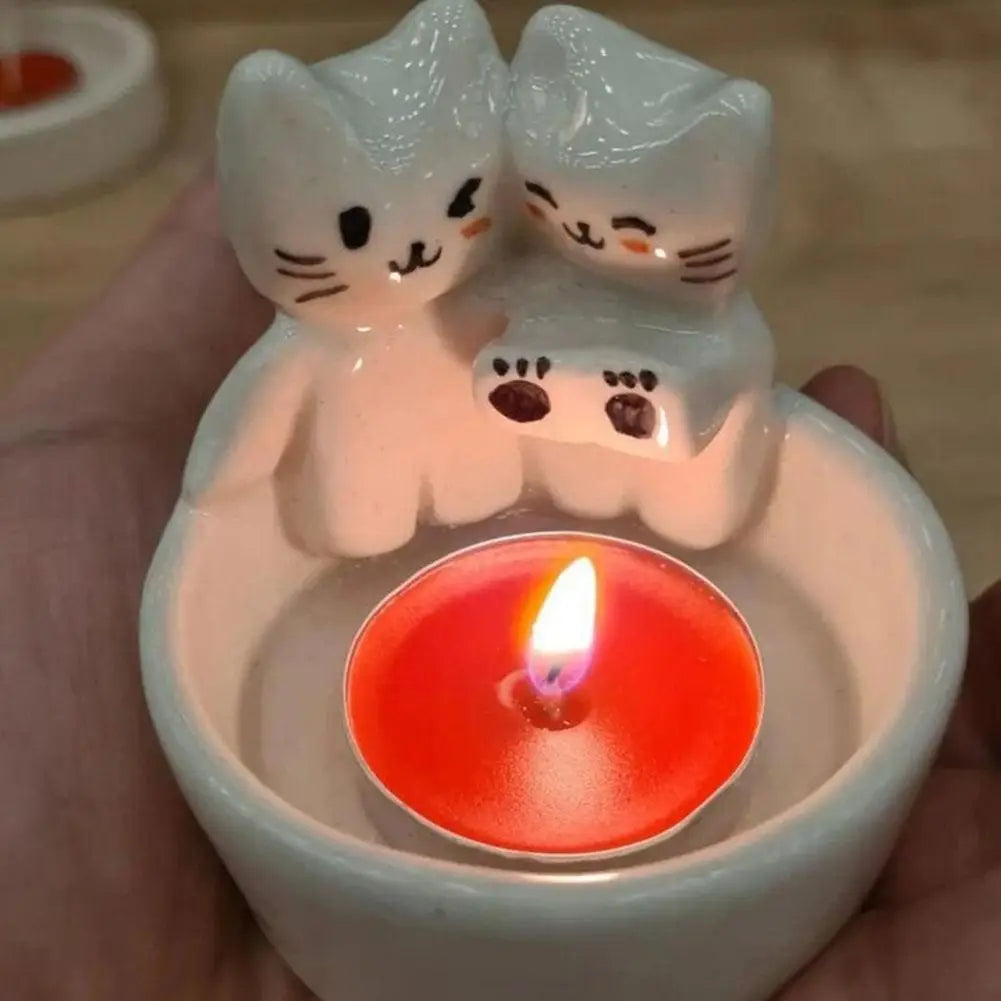Closeup of the cat-shaped tealight candle holder being held in a hand with a red tealight candle