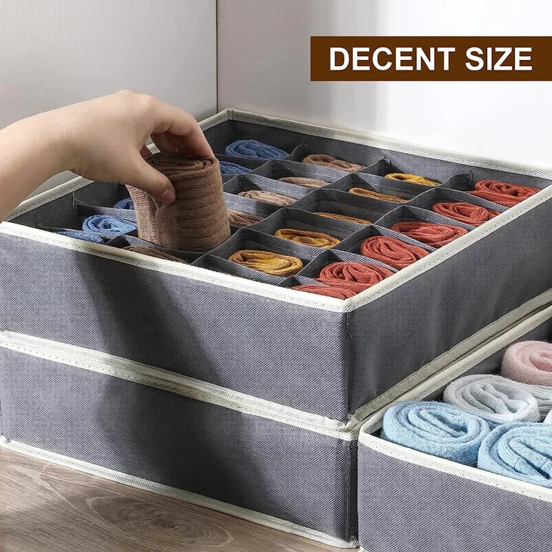 Close-up of a hand placing rolled socks into a gray fabric drawer organizer with multiple compartments