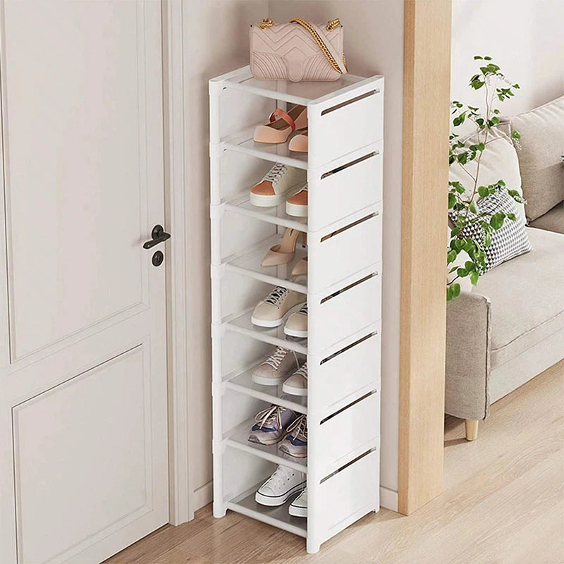 Single slim white shoe rack with several pairs of shoes by an interior door and living room.