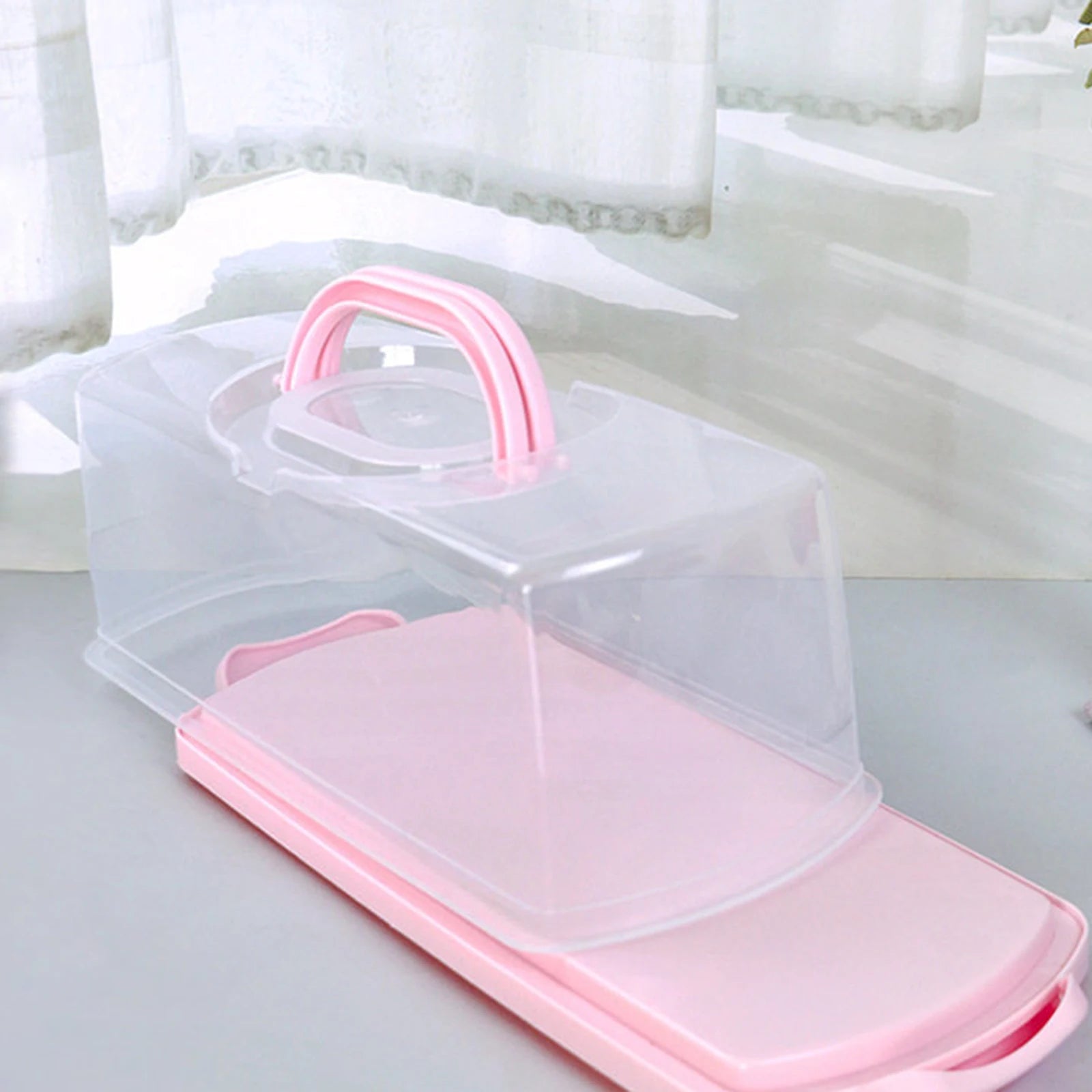 Empty rectangular bread keeper with clear lid and pink accents placed by a window