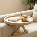 Round bamboo sofa armrest tray table holding coffee, snacks, and a book on a beige sofa