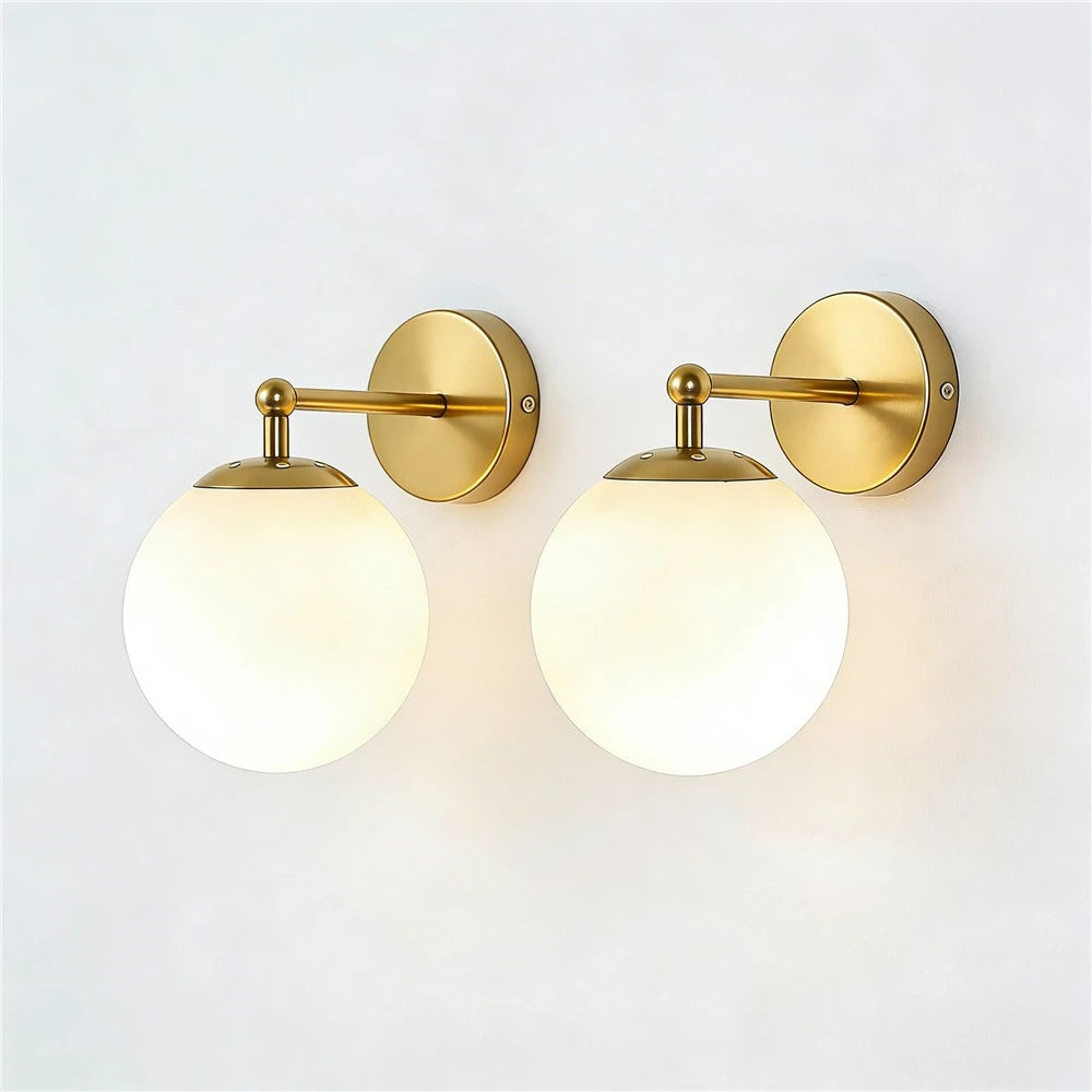 Pair of globe wall sconces with brass finish and frosted glass shades