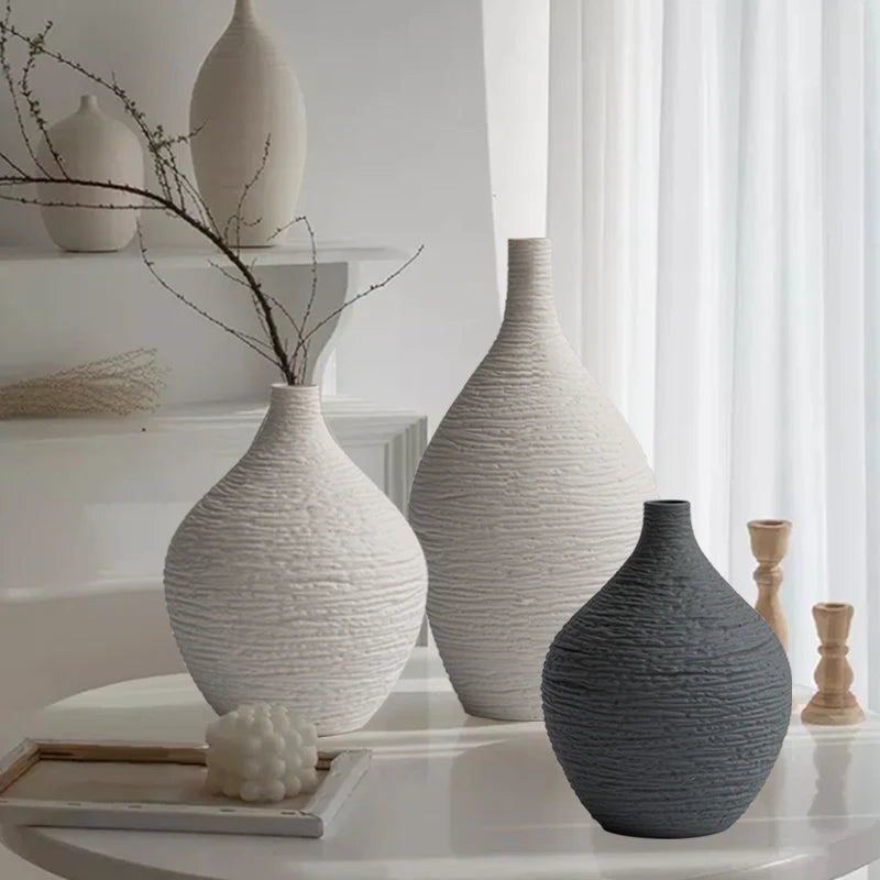 Three textured ceramic vases in beige and grey displayed on a modern white table in a living room