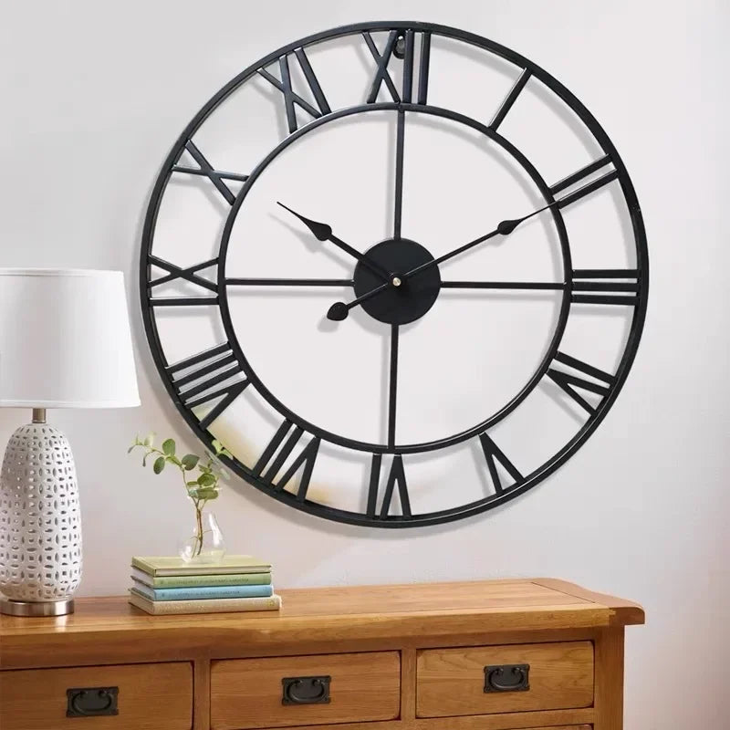 Metal wall clock with Roman numerals hanging above a wooden console in a living room