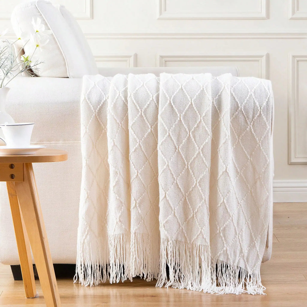 White diamond-pattern plaid knit throw blanket with fringe on sofa arm