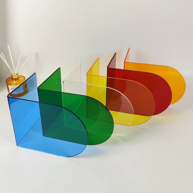 Four colorful arch-shaped acrylic bookends in blue, green, red, and yellow arranged on a white surface