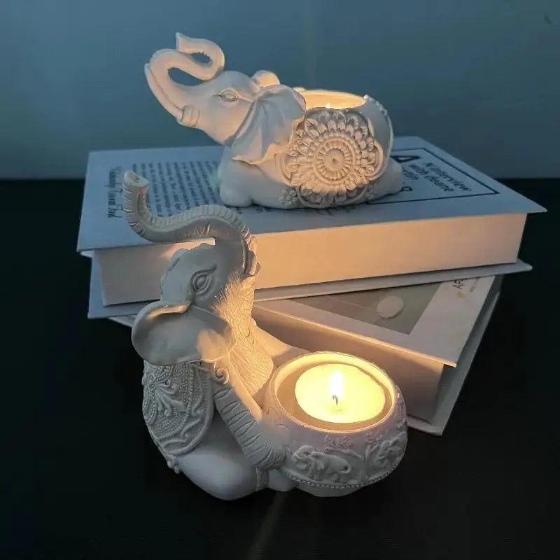 White elephant resin tealight candle holders with lit candles on stacked books, providing soft candlelight.