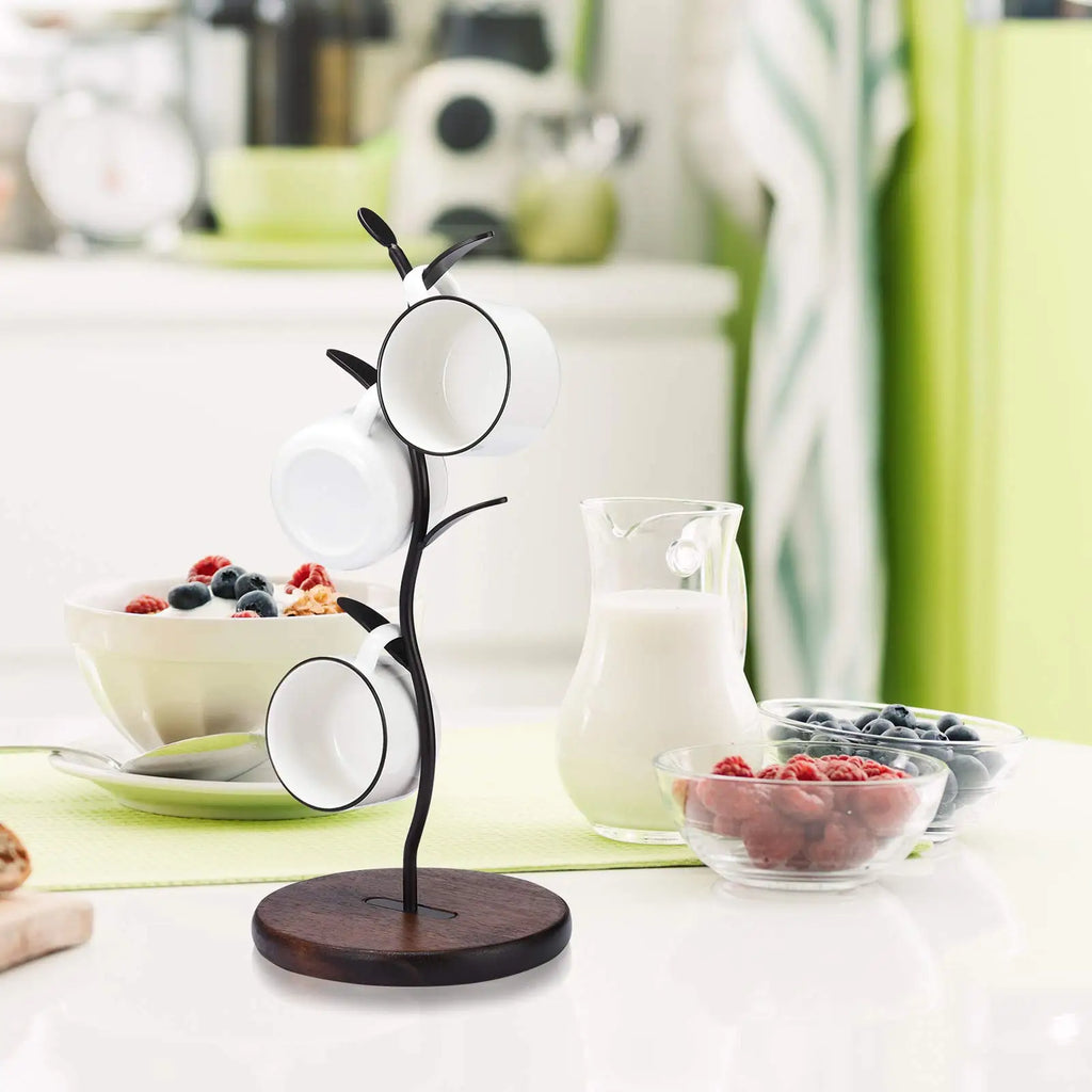 Mug tree stand holding mugs on a kitchen counter beside bowls of fruit and milk