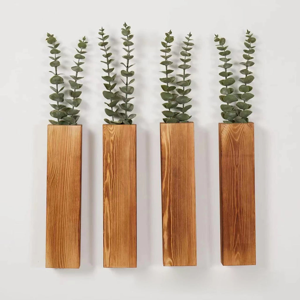 four vertical wooden wall planters with green artificial stems on a white wall