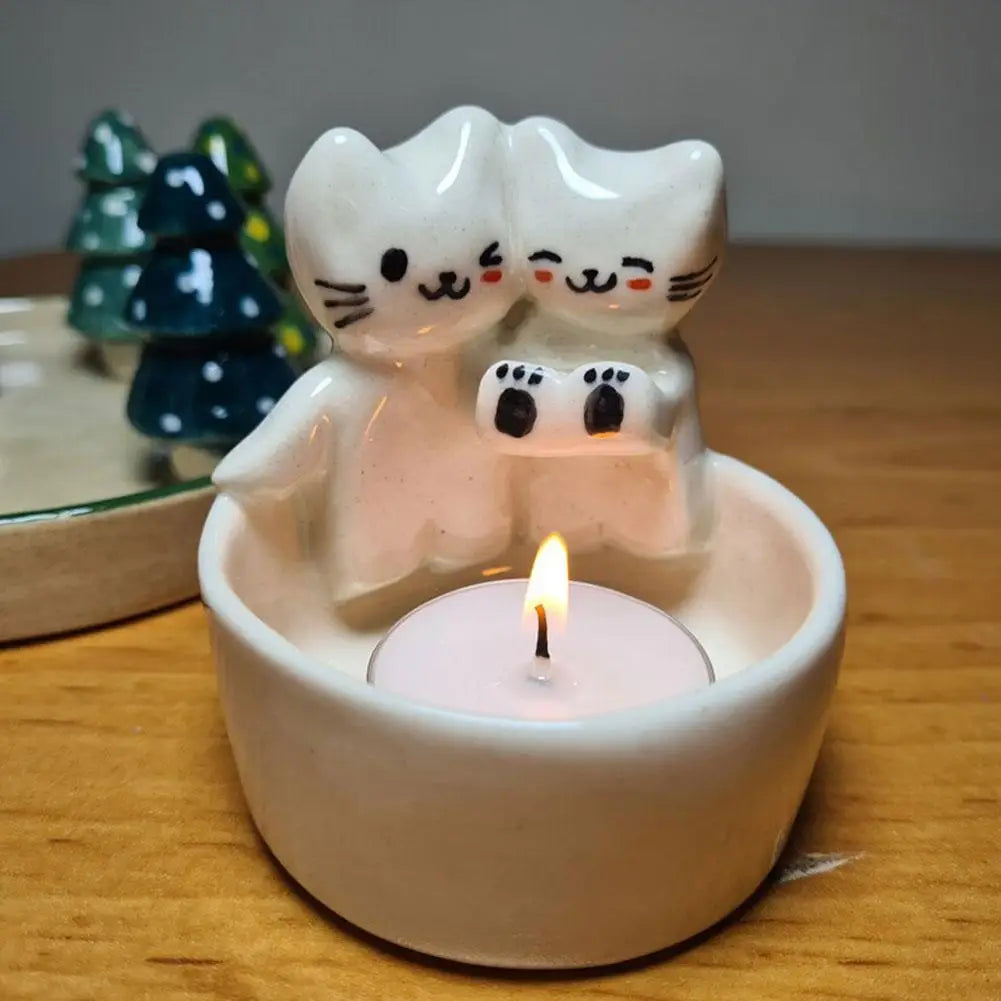 Polyresin cat tealight candle holder with two cartoon cats and a lit candle on a wooden table