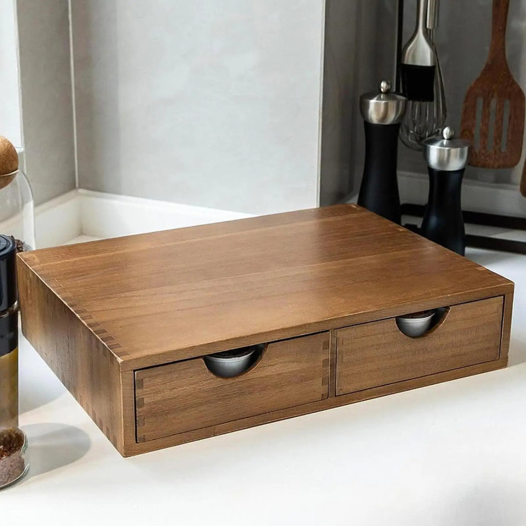 Wooden two-drawer coffee pod organizer on a kitchen counter with utensils nearby