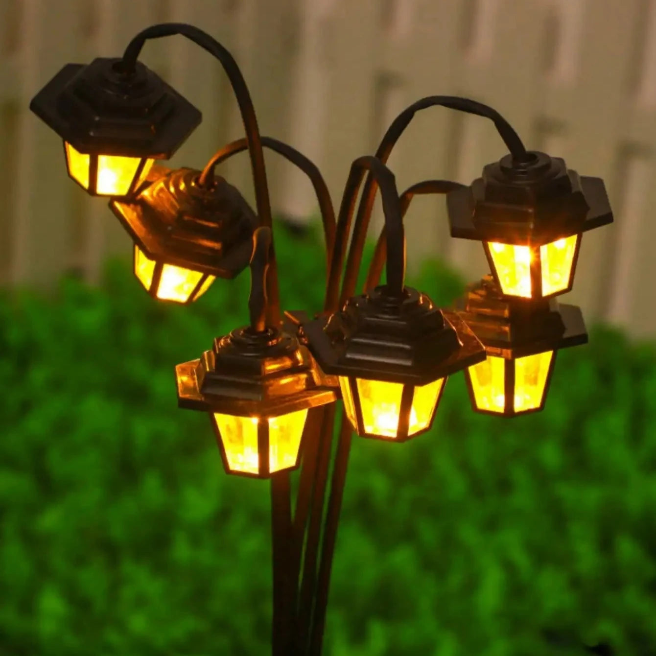 Solar retro lantern garden light with warm white LEDs illuminating in green garden setting