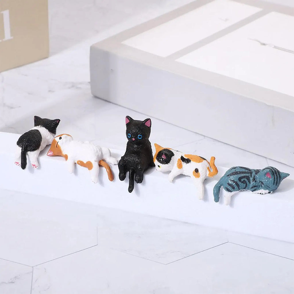 Cat figurine set lined up along a white shelf in a home or office setting