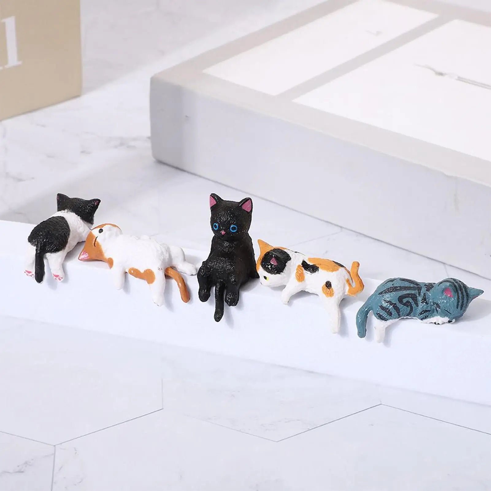 Cat figurine set lined up along a white shelf in a home or office setting