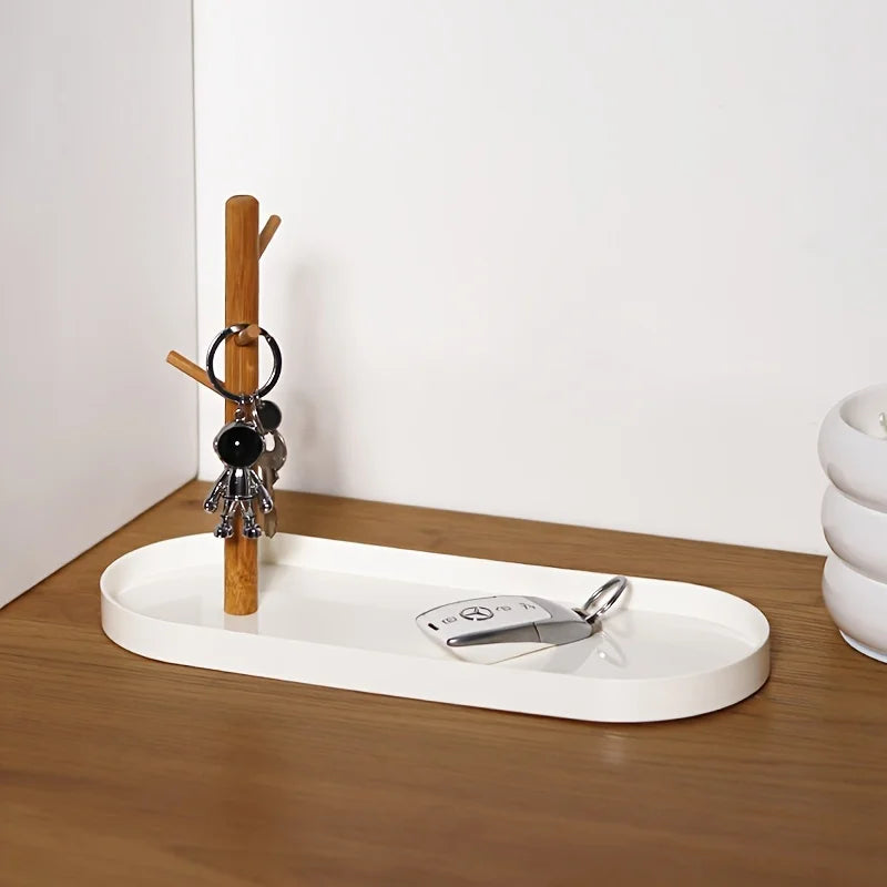 White key and jewelry tray with wooden tree stand on an entryway table, holding keychains and a car key
