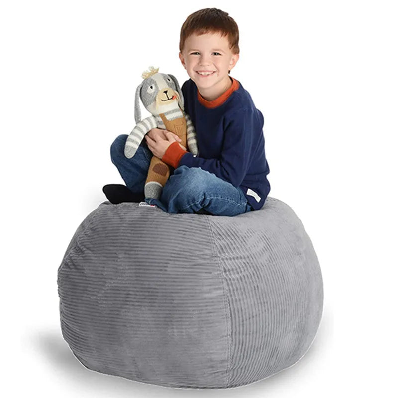 Child sitting on a gray round toy storage bean bag holding a stuffed animal