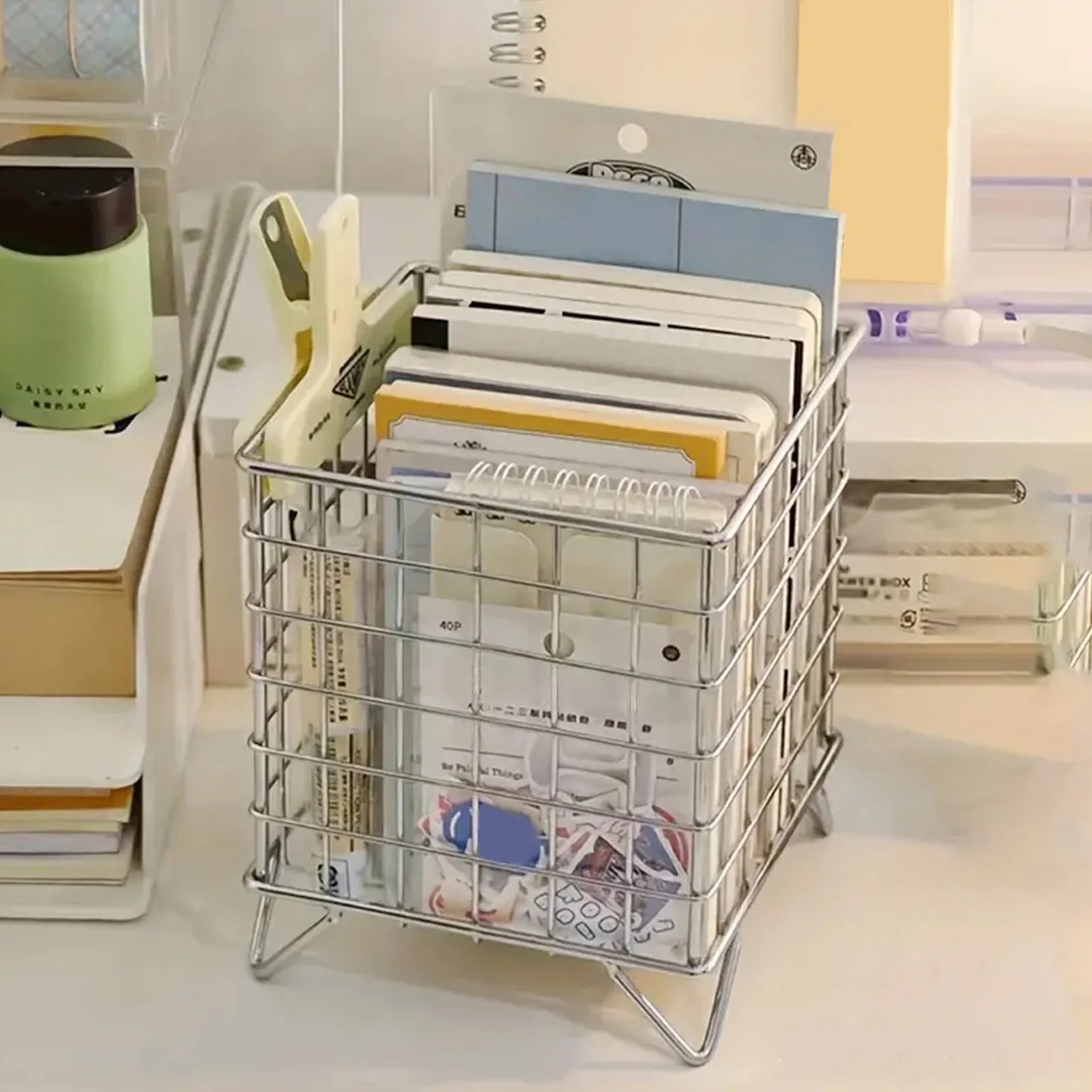 silver wire organizer basket containing stationery and notebooks on a desk