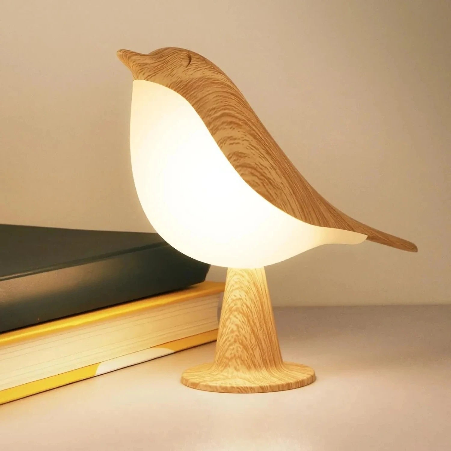 Bird-shaped desk lamp with glowing body next to books