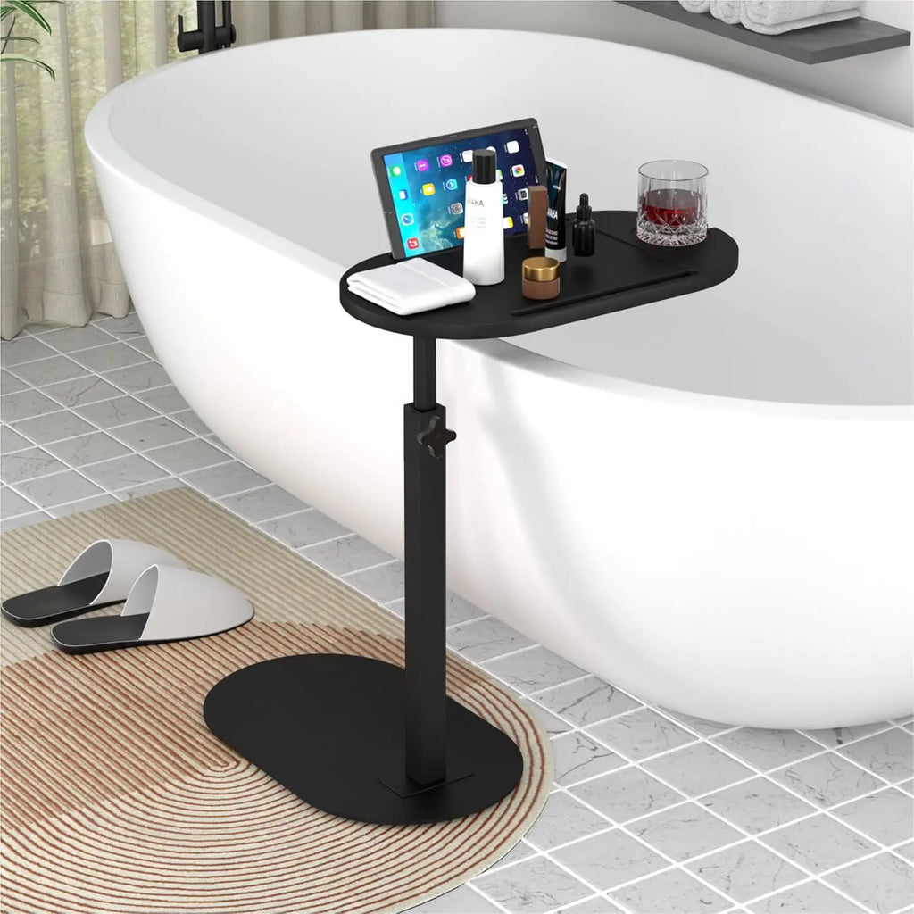 Black freestanding bathtub tray holding a tablet and bath essentials next to a modern white bathtub