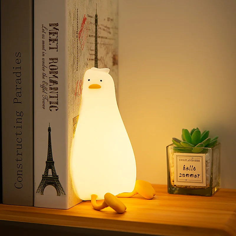 Duck silicone night light sitting upright on a bedroom shelf beside books