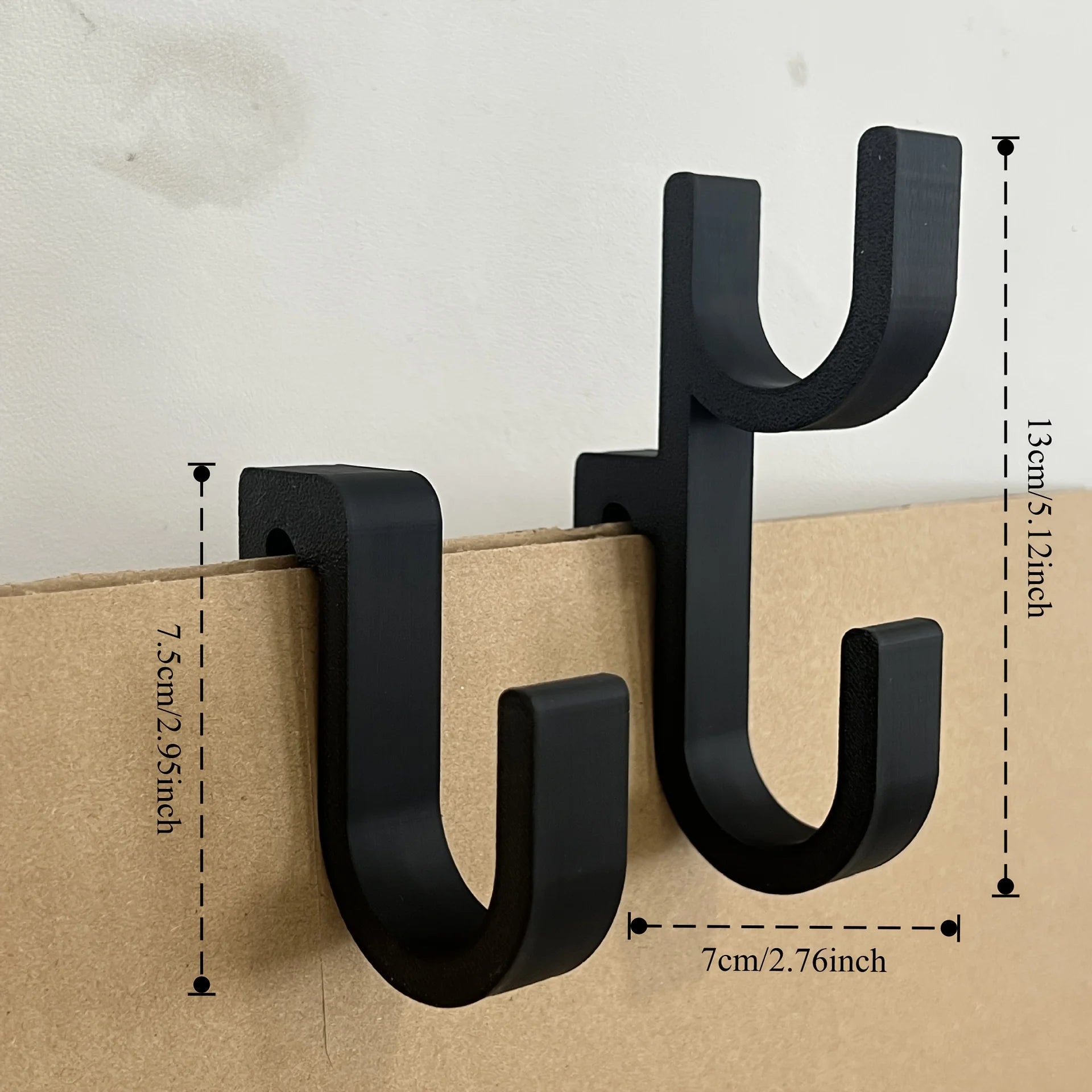 Single and double black plastic car trunk hooks with size measurements on a plain background
