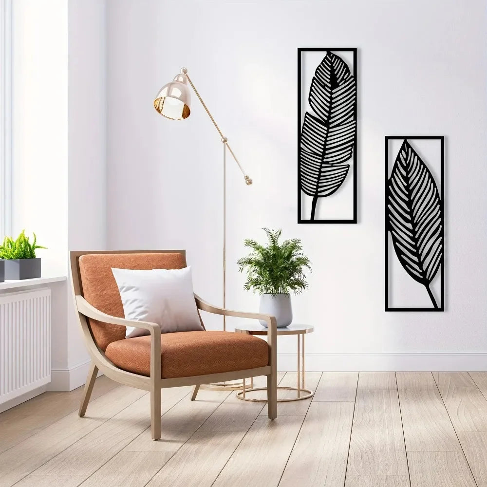 Modern living room with two black metal leaf wall art panels on a white wall above an orange armchair