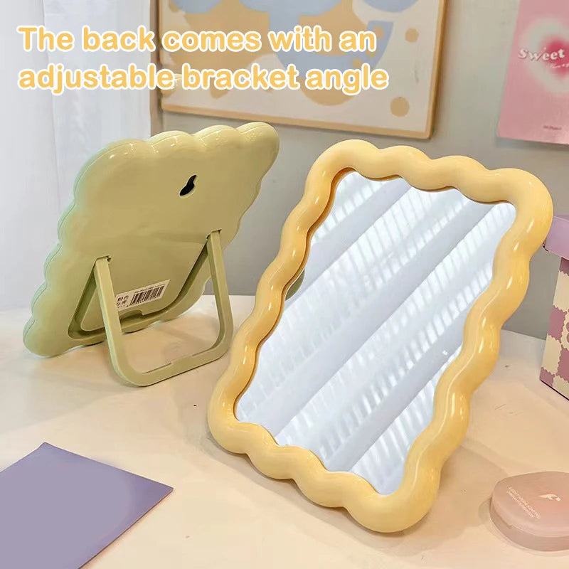 Yellow and green wave edge makeup mirrors on a desk, one standing and one showing the adjustable bracket.