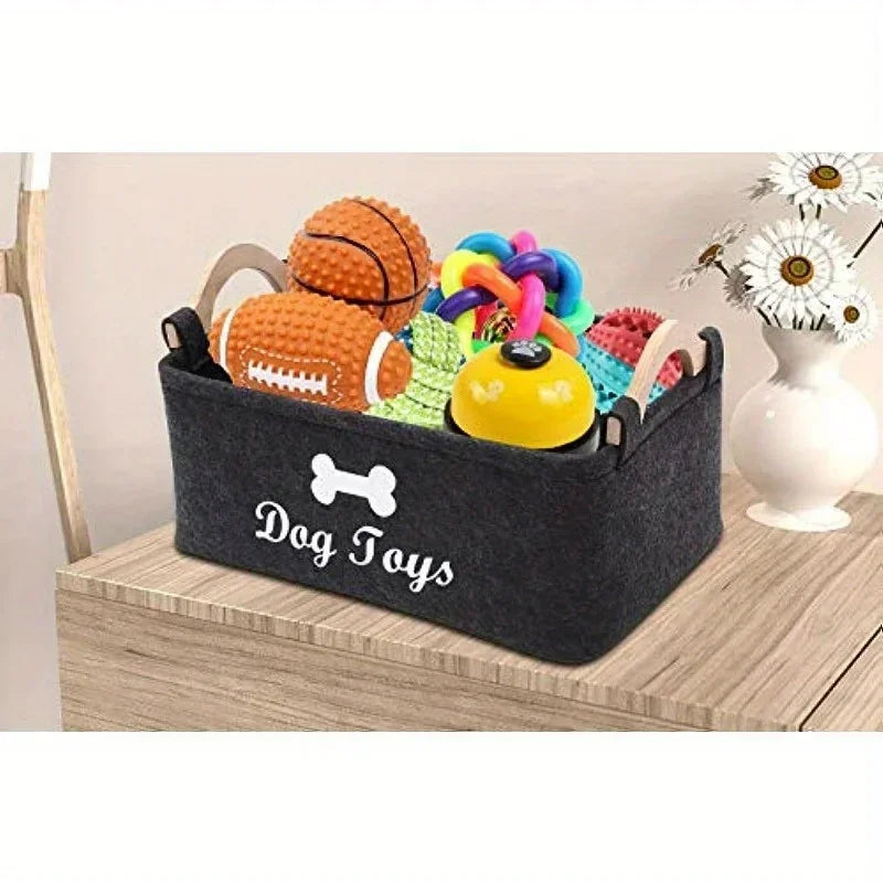 Felt dog toy basket filled with toys on a light wood table beside a vase